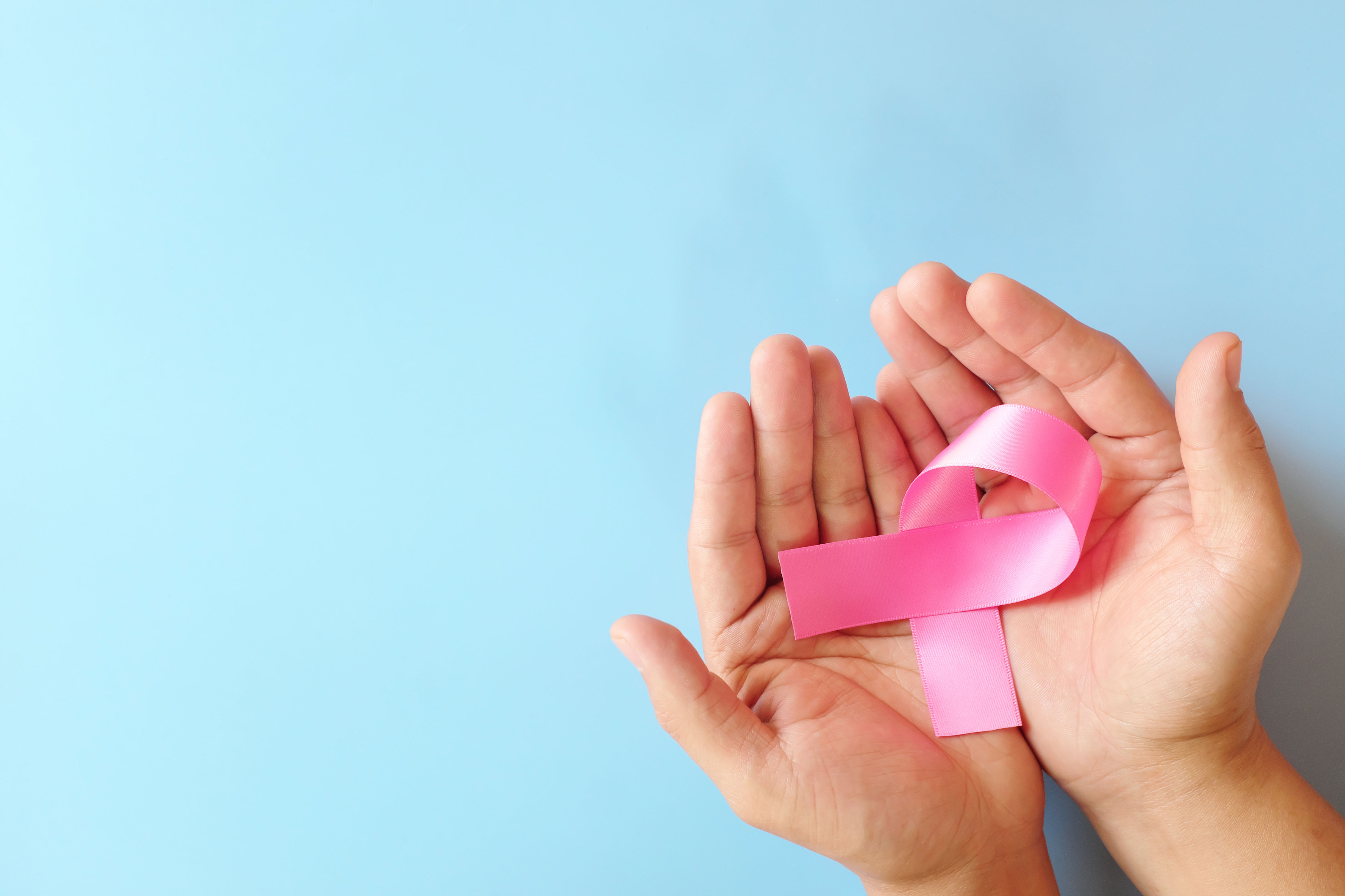 Hands holding a pink ribbon
